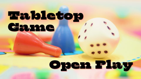 two game pawns, a 6-sided die, and a blurry board game with the text tabletop game open play